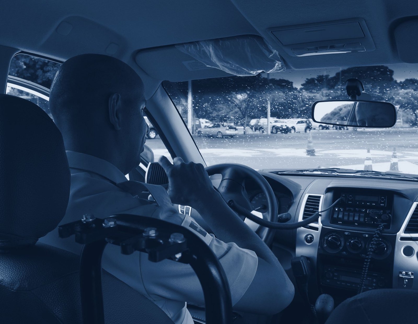 Policial militar ao volante de uma viatura, usando o rádio